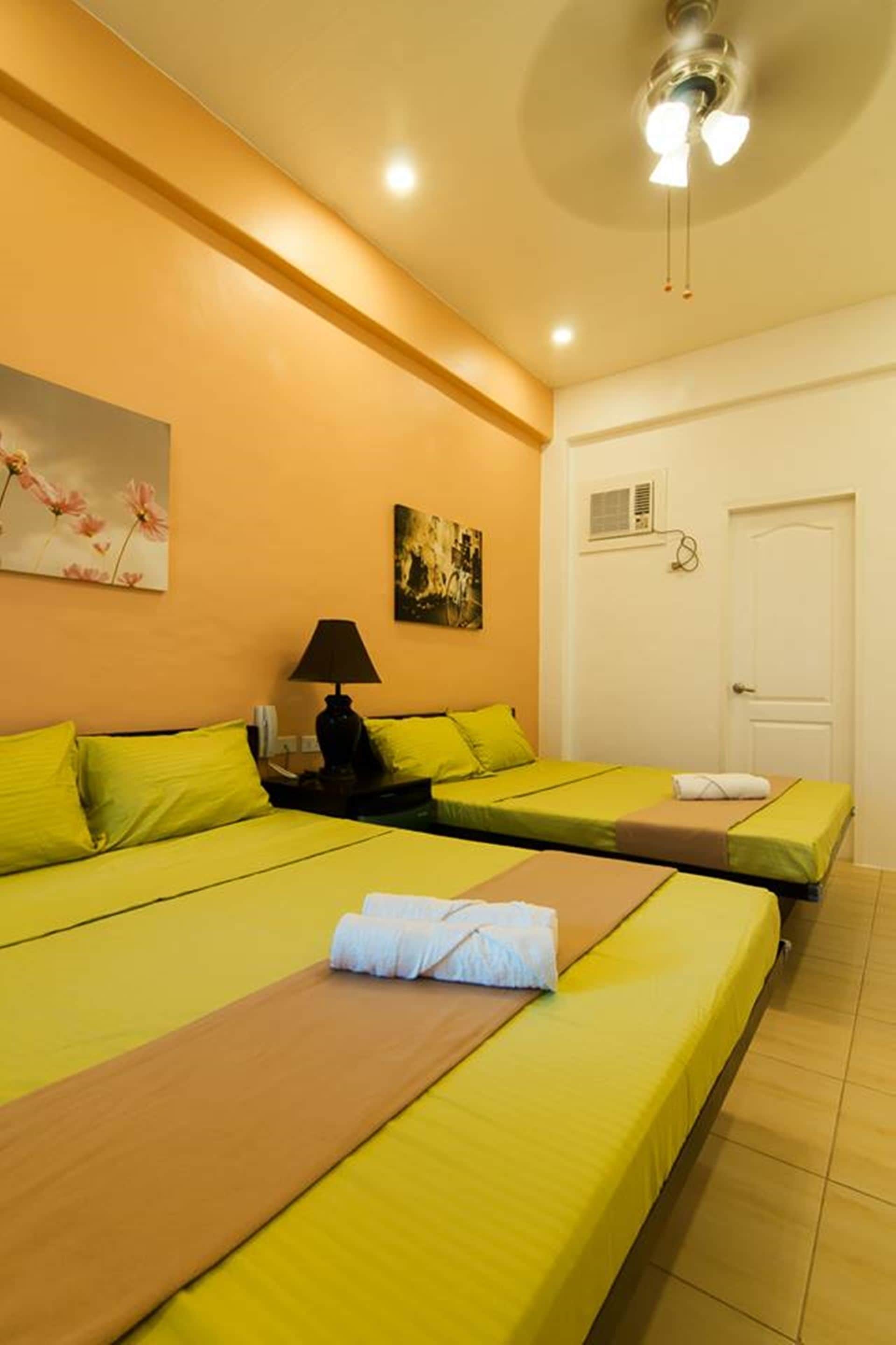 Habitación de hotel con dos camas, una mesita de noche, una lámpara y obras de arte en las paredes.