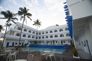 A hotel with a pool, outdoor seating, and palm trees. - Brizo Hotel and Resort Tagaytay (Silang)