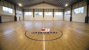 An indoor basketball court with a high ceiling and large windows.