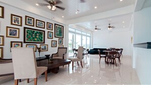 A spacious dining area with a high ceiling, multiple ceiling fans, and a wall adorned with framed artwork.