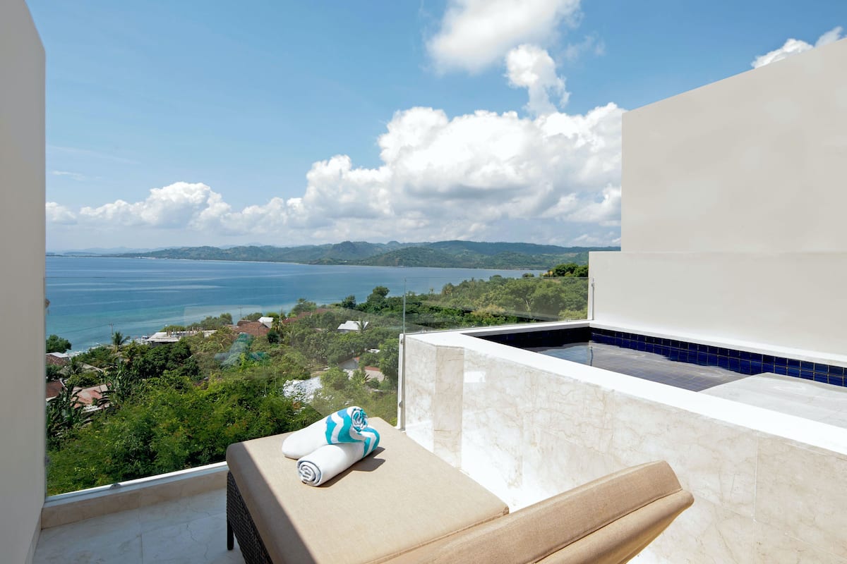 A balcony with a view of the sea, a towel, and a lounge chair.