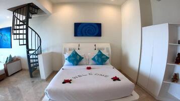 Un dormitorio moderno con una cama curva, una escalera en espiral, una obra de arte azul en la pared y un armario blanco.