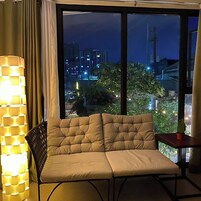 A room with a cushioned sofa, a lamp, and a view of a cityscape at night.
