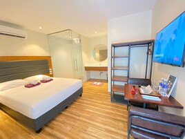 Habitación de hotel con cama, escritorio con silla, televisor, armario y baño.