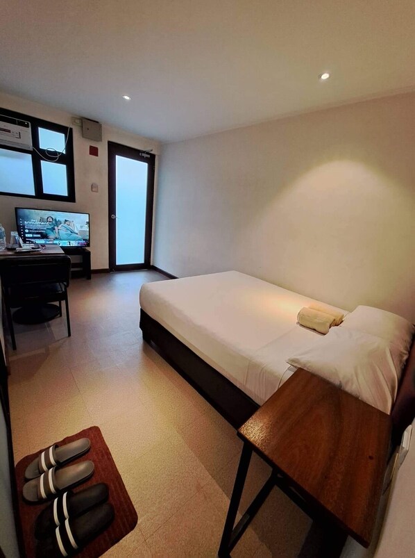 Una habitación de hotel compacta con una cama individual, un escritorio con ordenador y televisión.