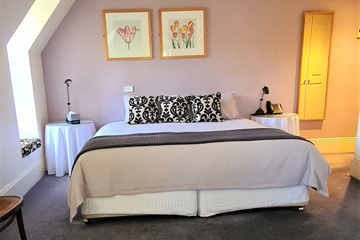 Un dormitorio con una cama grande, una mesita de noche, una lámpara y un cuadro en la pared.