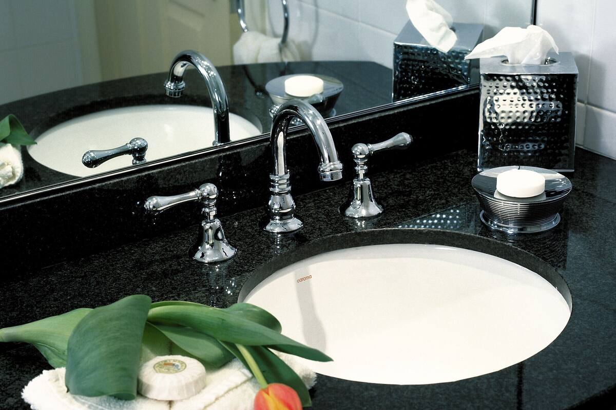 Un baño con lavamanos doble, espejo, toalla y caja de pañuelos.