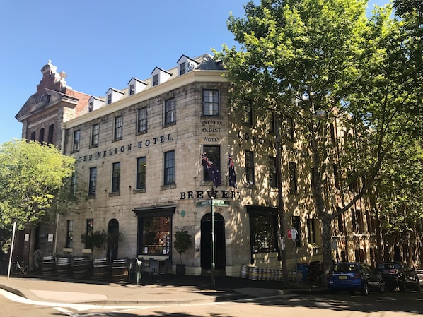 The exterior of the Ord Nelson Hotel, featuring a brick facade, large windows, and a sign indicating it is a brewery.