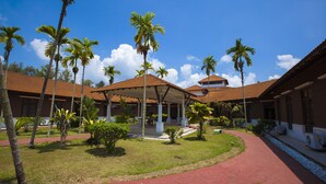 A courtyard with palm trees, a covered seating area, and a pathway. - Villea Morib (Banting)