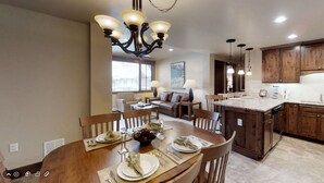 A modern kitchen with wooden cabinets, a central island, and a dining area with a chandelier. - 2 Bd Grand Lodge Peak 7 - sleeps 8 (Breckenridge)