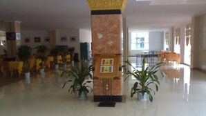 A spacious lobby with a polished marble floor, yellow tables, and potted plants. - Royal Hotel Luang Namtha ' Huang Ching' (Luang Namtha)