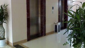 An elevator in a hallway with marble walls and potted plants. - Royal Hotel Luang Namtha ' Huang Ching' (Luang Namtha)