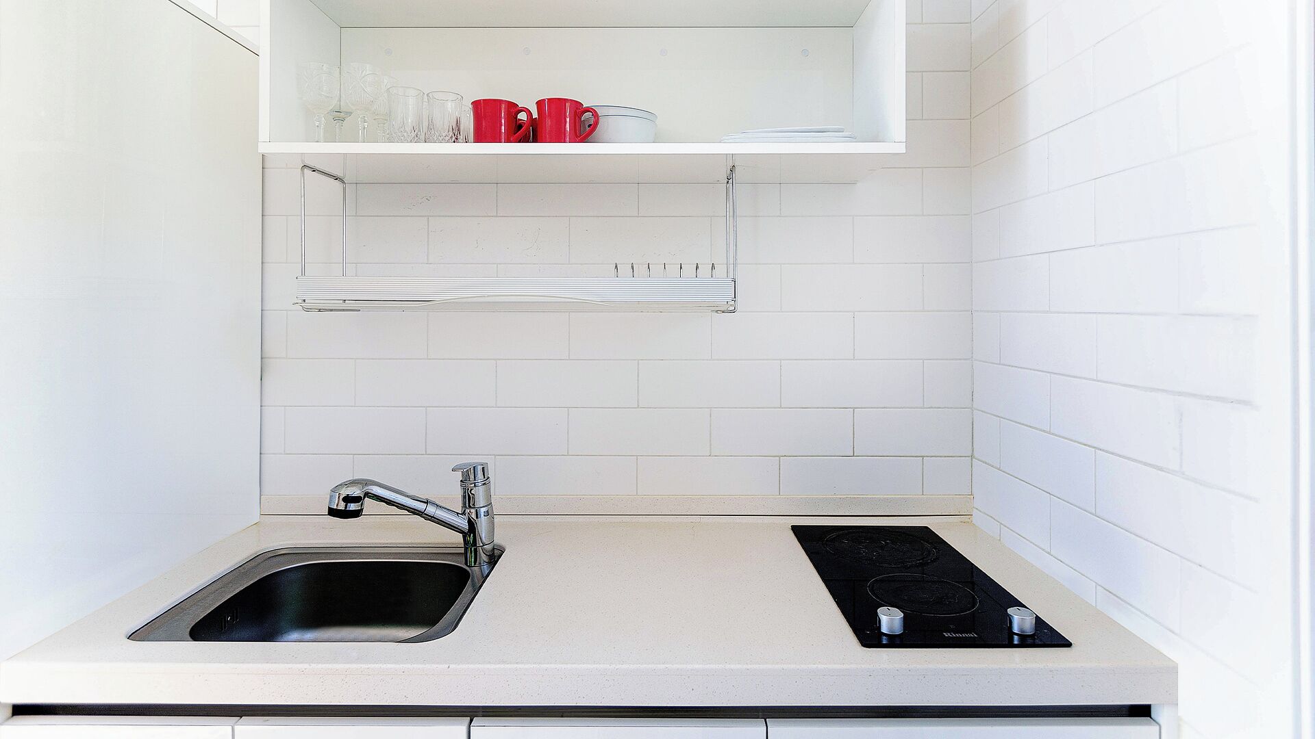 Cocina compacta con un lavamanos, dos hornillas y una encimera.