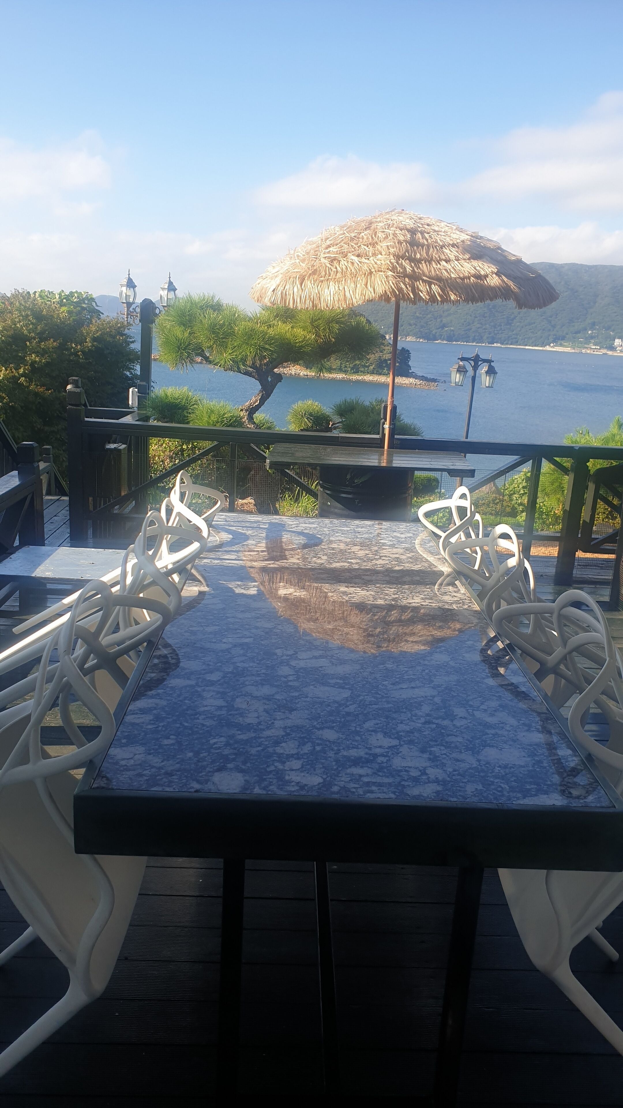 A table with chairs, an umbrella, and a view of the water.