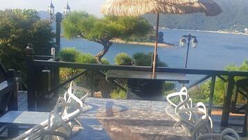 A table with chairs, an umbrella, and a view of the water.