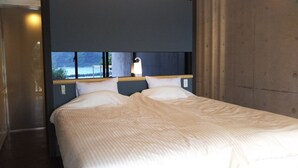 A hotel room with a bed, a headboard, and a window with a view of the sea. - Blue Suites Hanamuro on the beach (Zamami)