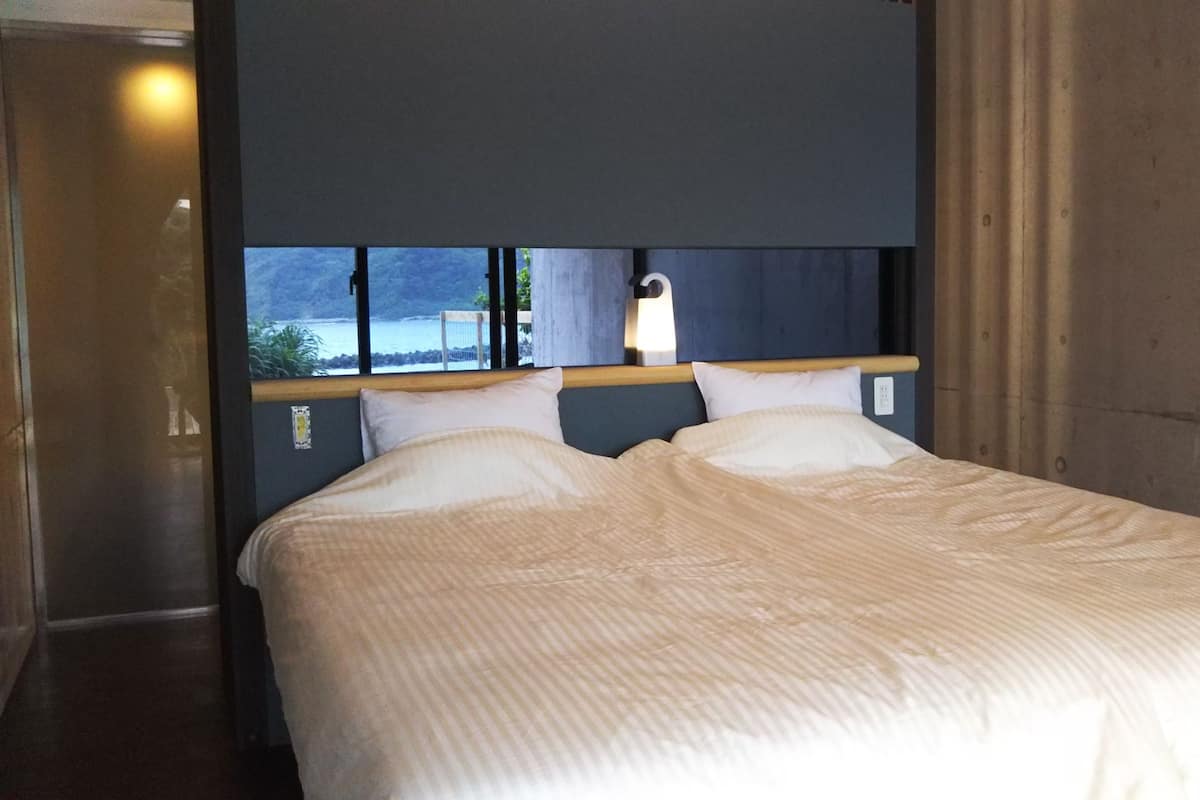 Ett hotellrum med en säng, en sänggavel och ett fönster med utsikt över havet.