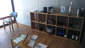 A room with a wooden floor, a desk with a chair, a bookshelf with various items, and a window. - Blue Suites Hanamuro on the beach (Zamami)