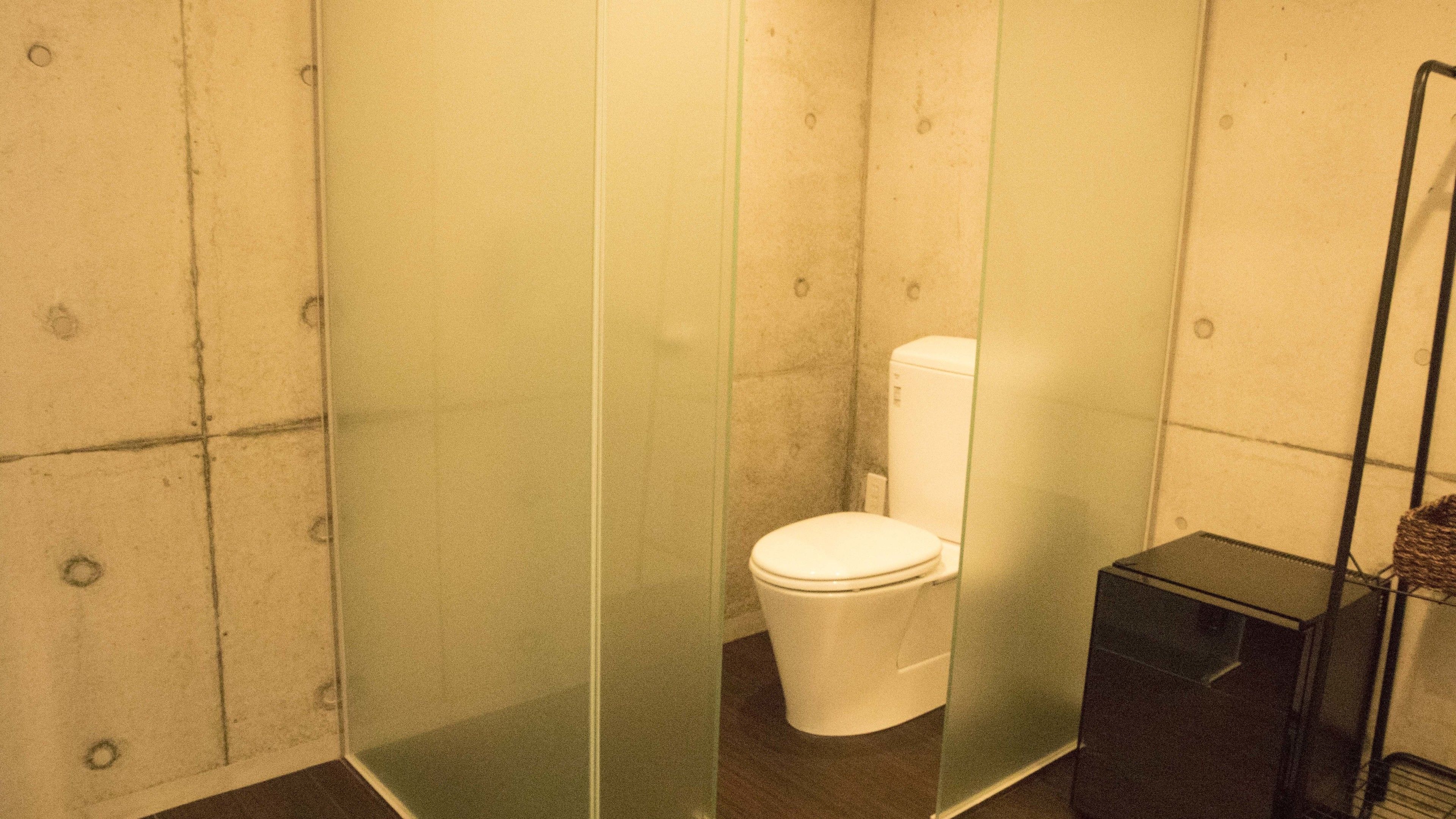A small, enclosed bathroom with a toilet and a glass partition.
