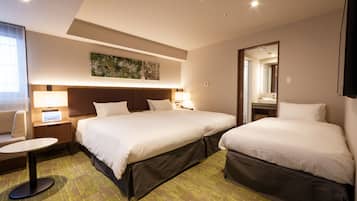 A hotel room with two beds, a small table, a chair, and a large window.