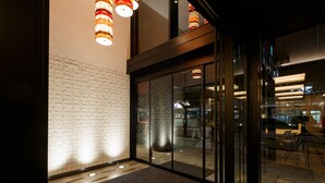 A modern hotel lobby with patterned walls, a carpeted floor, and glass doors leading to the reception area. - Hotel Forza Kanazawa (Kanazawa)