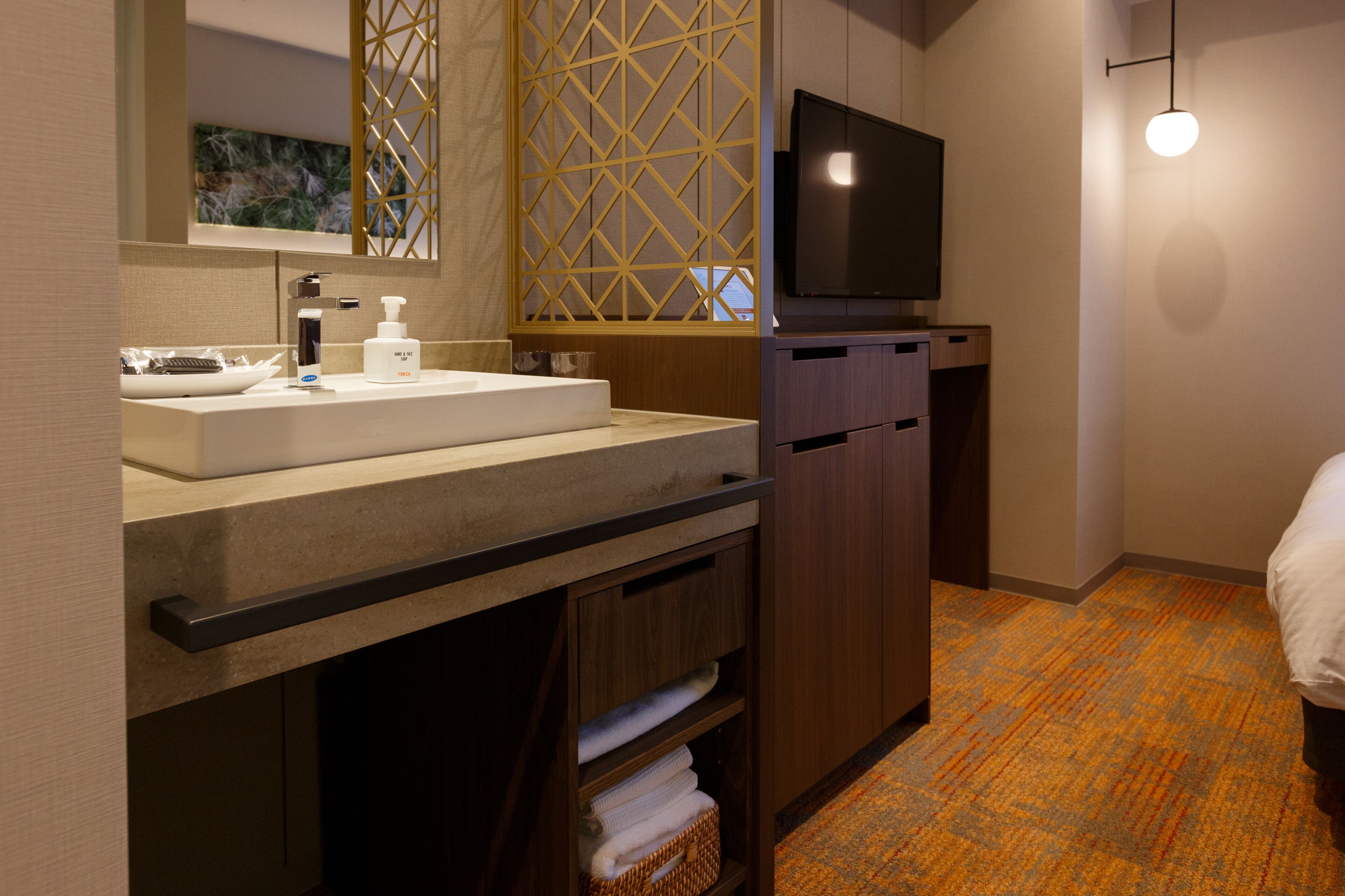 A modern bathroom with a large sink, mirror, and wooden cabinet.
