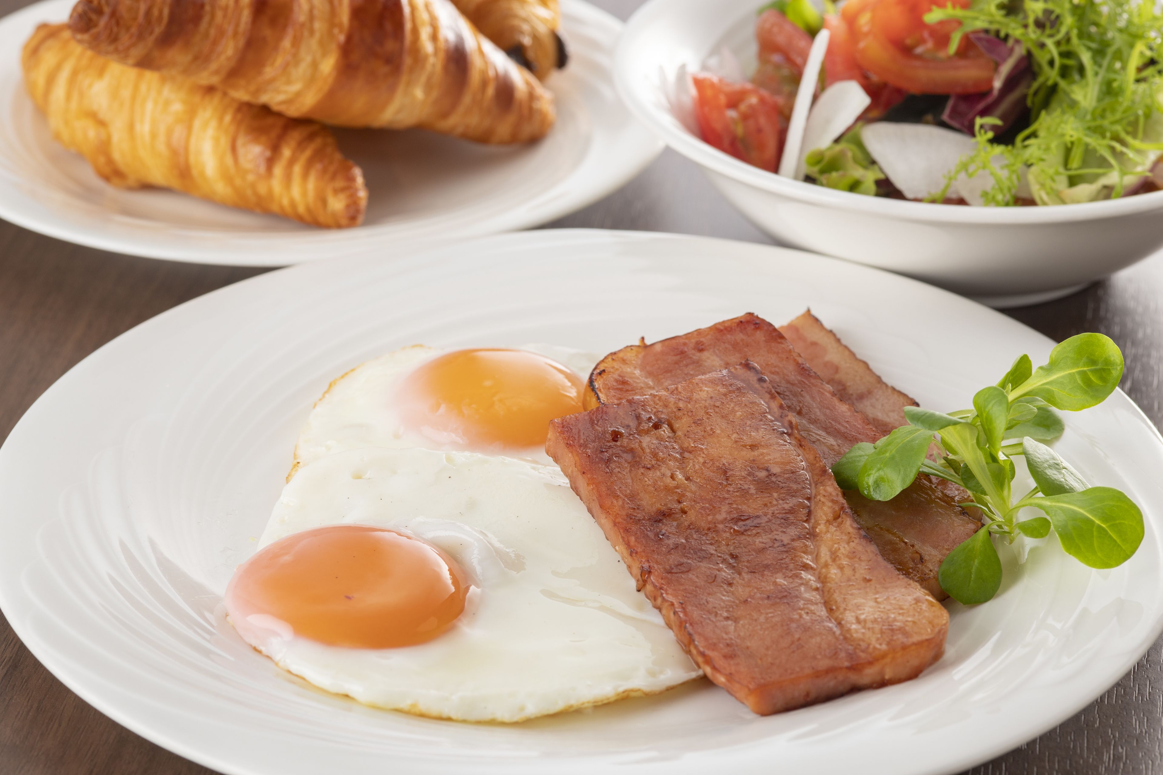 Ein Teller mit Eiern, Speck und Croissants.