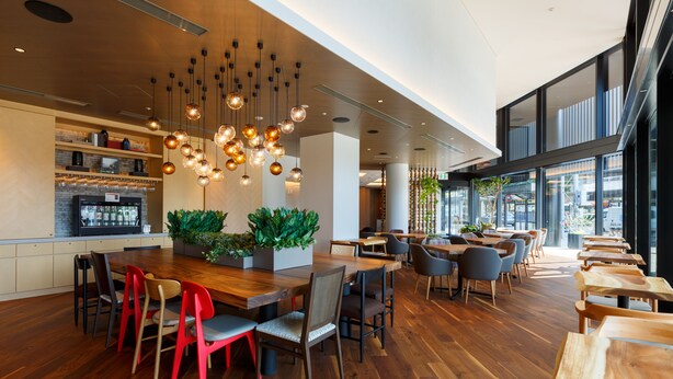 A modern restaurant with wooden tables and chairs, hanging light fixtures, and large windows. - Hotel Forza Kanazawa (Kanazawa)