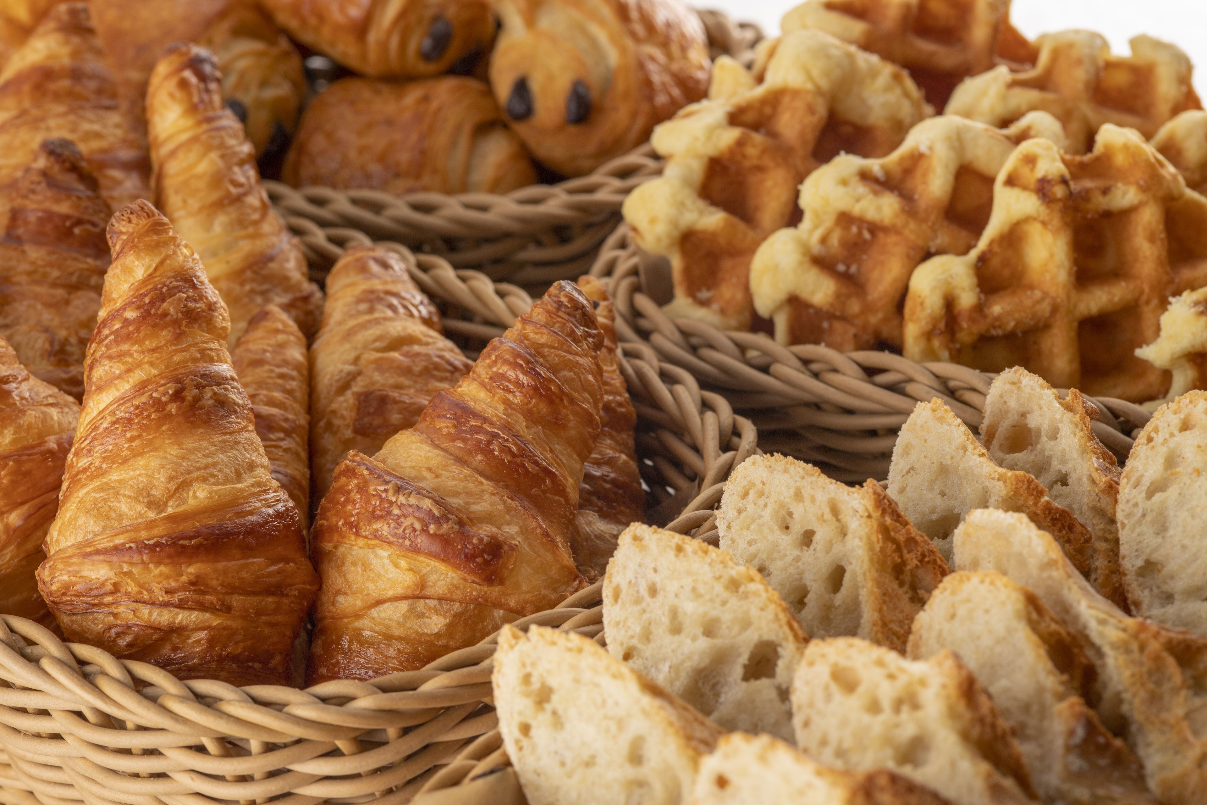 A basket filled with various types of bread and pastries, including croissants and baguettes.