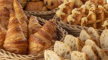 A basket filled with various types of bread and pastries, including croissants and baguettes.