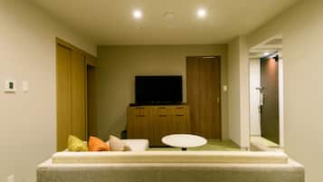 A modern living room with a flat-screen TV, a sofa, a small table, and wooden cabinets.