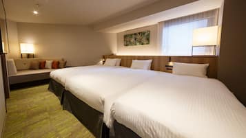 Quarto de hotel com duas camas grandes, um sofá, um abajur e um quadro na parede.