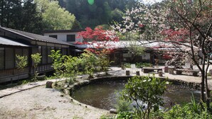 A traditional Japanese garden with a pond, stone lanterns, and cherry blossoms.