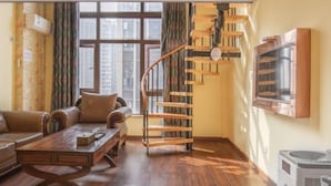 A living room with a wooden staircase, a sofa, a coffee table, and a TV mounted on the wall. - Sucha Hotel Chongqing Danzishi Laojie (Chongqing)