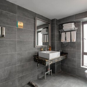 A modern bathroom with dark tiles, a white sink, a large mirror, and a towel rack. - Sucha Hotel Chongqing Danzishi Laojie (Chongqing)