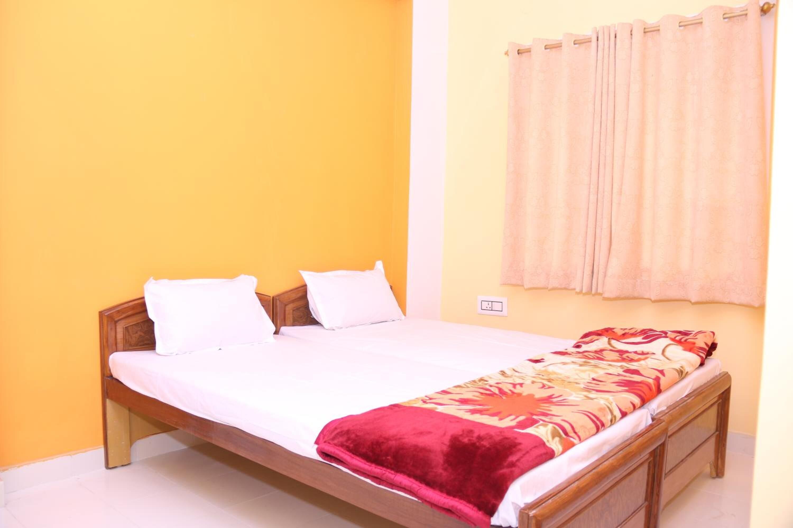 A single bed with a wooden frame, white bedding, and a red blanket.