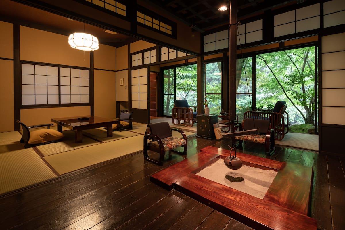 A traditional Japanese-style room with tatami flooring, low wooden tables, and chairs.
