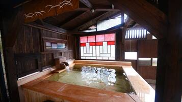 A traditional wooden bathhouse with a wooden bench and a stone basin.
