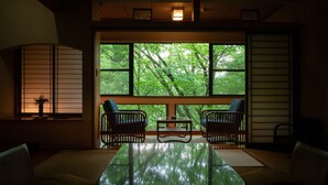 A traditional Japanese room with tatami flooring, a low table, and two chairs. - Sanso Tensui (Hita)