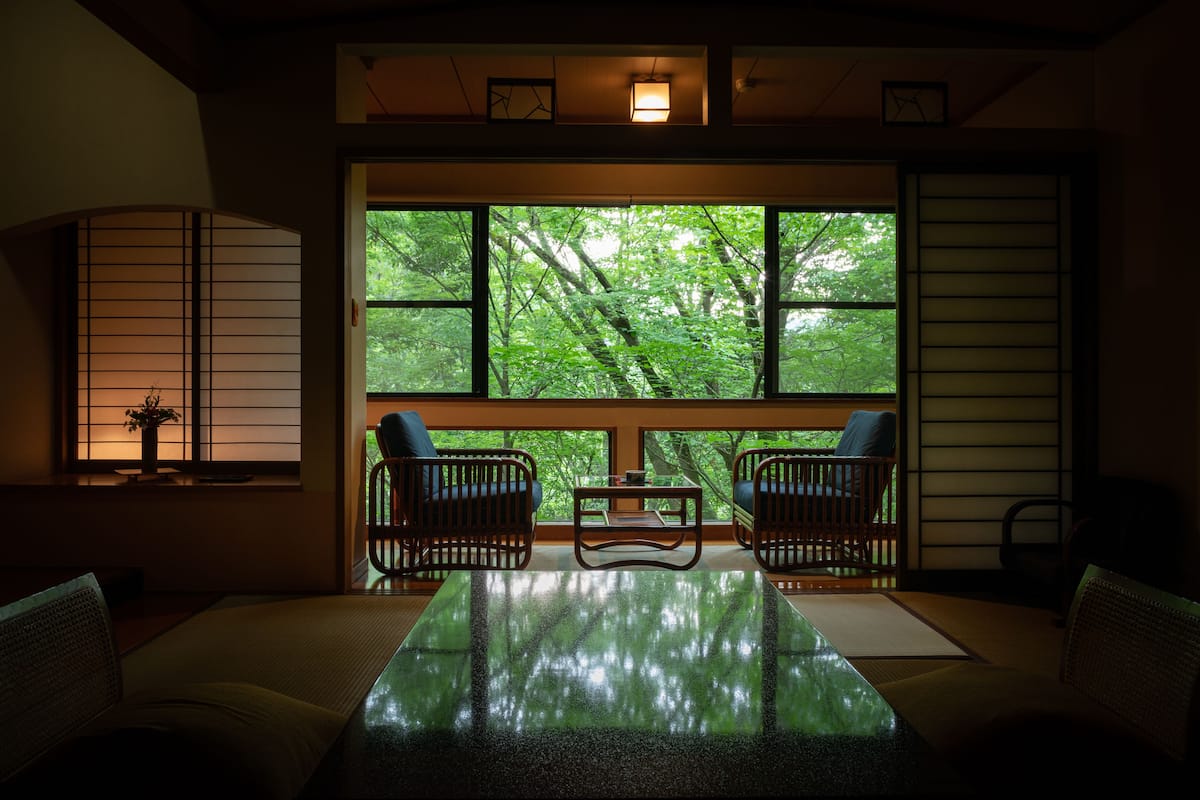 A traditional Japanese room with tatami flooring, a low table, and two chairs.