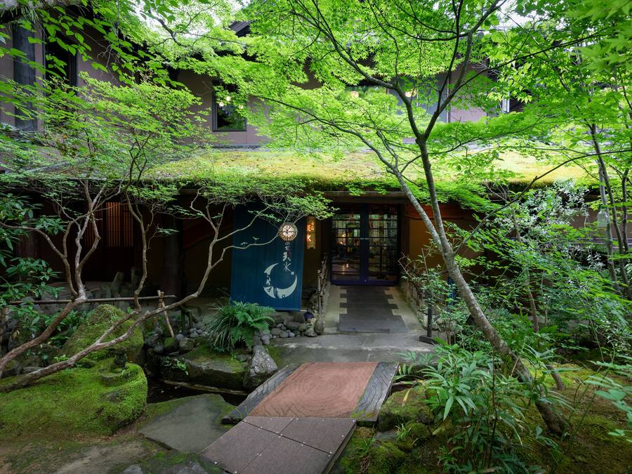 En traditionel japansk have med en stensæt sti, der fører til en træport.