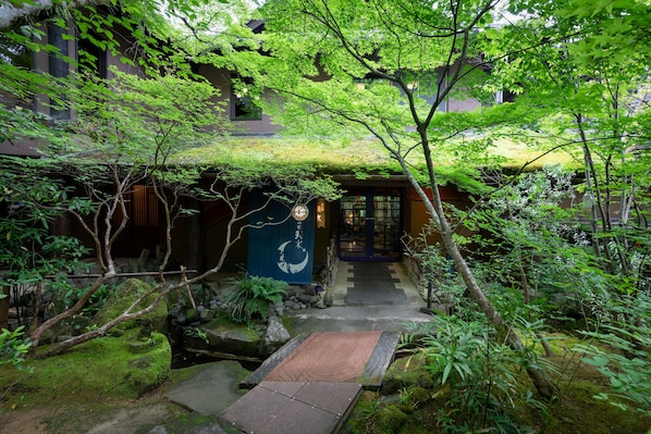 Ein traditioneller japanischer Garten mit einem Kiesweg, der zu einem hölzernen Tor führt.