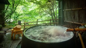 A hot spring bath with a wooden bench and railing, surrounded by lush greenery. - Sanso Tensui (Hita)