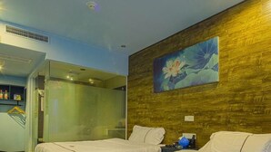Une chambre d’hôtel avec deux lits, un espace douche et un tableau au mur.