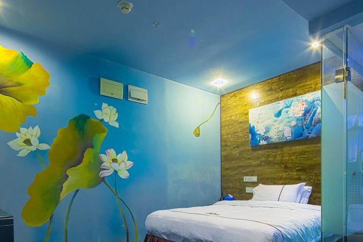 Une chambre à coucher avec un lit, une fresque murale représentant des fleurs, un mur d’accent en bois et une cabine de douche en verre.