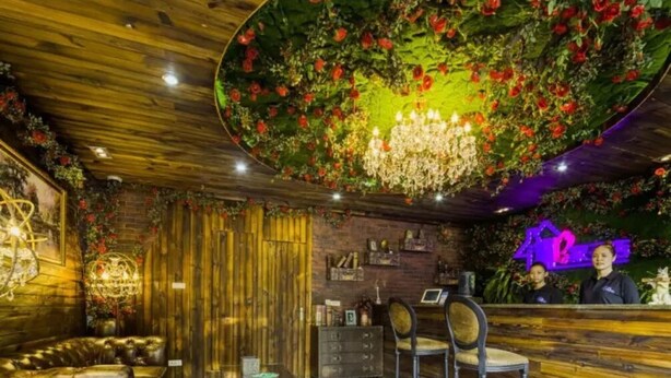 Un intérieur chaleureux avec un plafond en bois, un lustre, un comptoir d’accueil et un canapé en cuir.