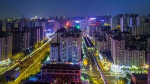Une vue nocturne d’une ville, avec ses gratte-ciel, ses rues illuminées et un pont imposant.