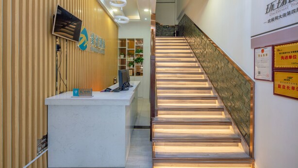 A hotel reception area with a wooden panel wall, a reception desk, a staircase with illuminated steps, and various signs and certificates on the walls. - Sucha Hotel Chengdu Wuhouci Jinli (Chengdu)