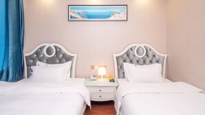 A hotel room with two beds, a nightstand with a lamp, a painting of a coastal landscape, and a blue curtain. - Sucha Hotel Chengdu Wuhouci Jinli (Chengdu)