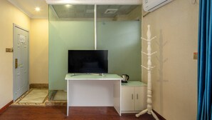 A room with a TV on a white desk, a coat rack, and a door. - Sucha Hotel Chengdu Wuhouci Jinli (Chengdu)